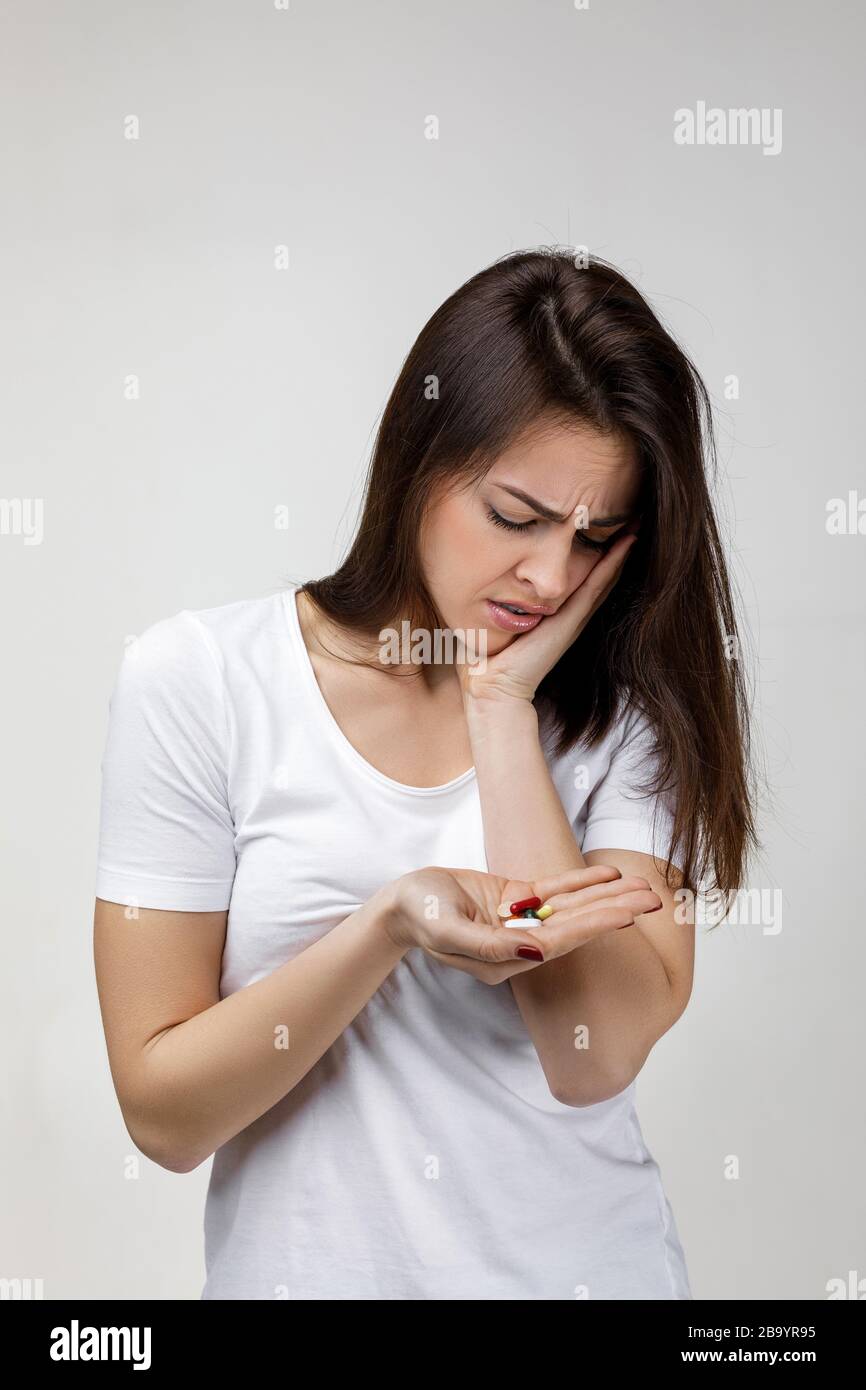 jeune femme triste avec la médecine souffrant de la douleur de dent, des caries. fille ayant mal à la dent et prenant la pilule. Concept de santé et de soins dentaires Banque D'Images