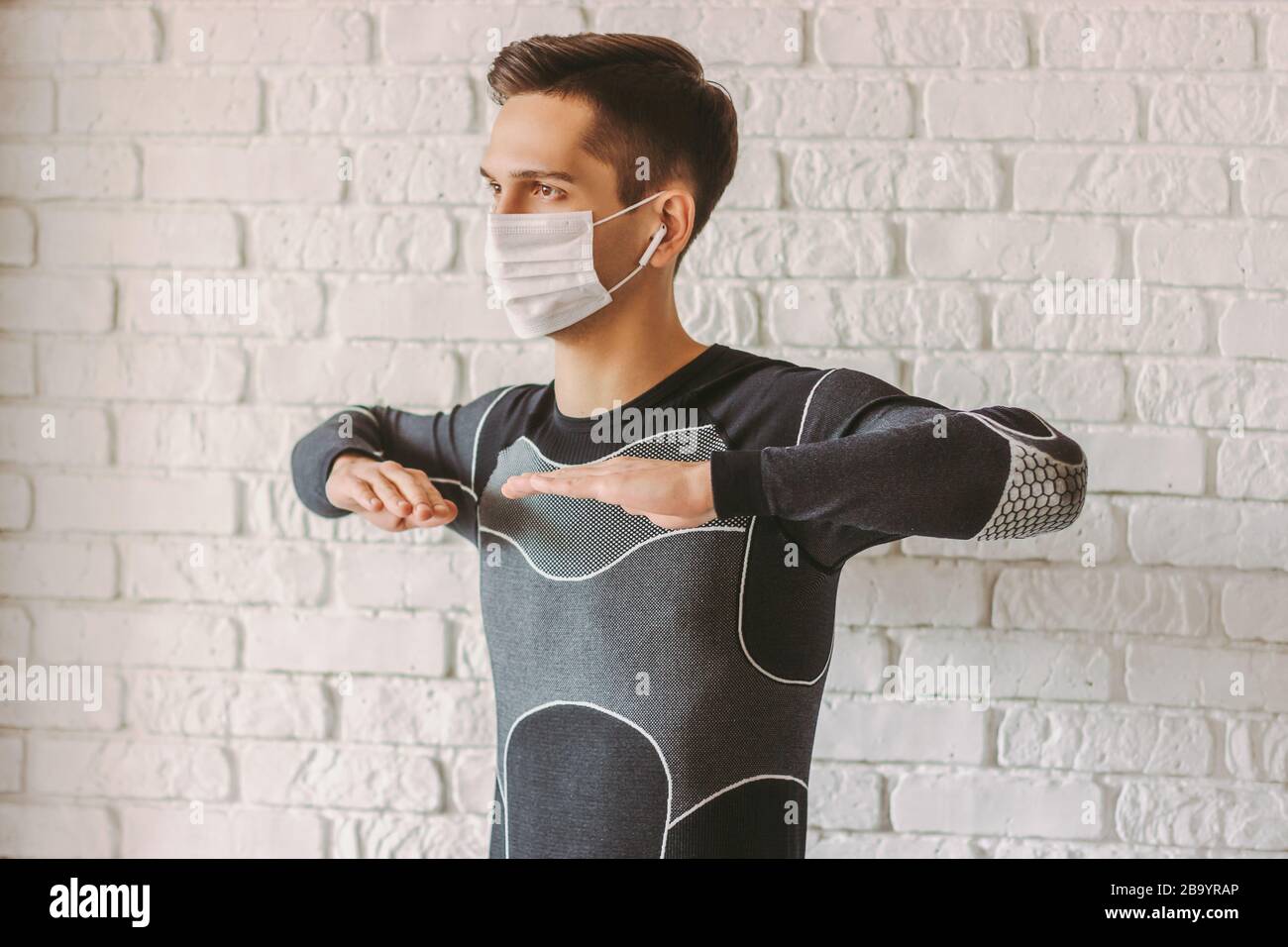 Entraîneur professionnel de forme physique jeune homme dans le masque de protection du visage faisant des exercices d'entraînement. Sport homme dans le masque médical sur le visage faisant des exercices d'étirement Banque D'Images