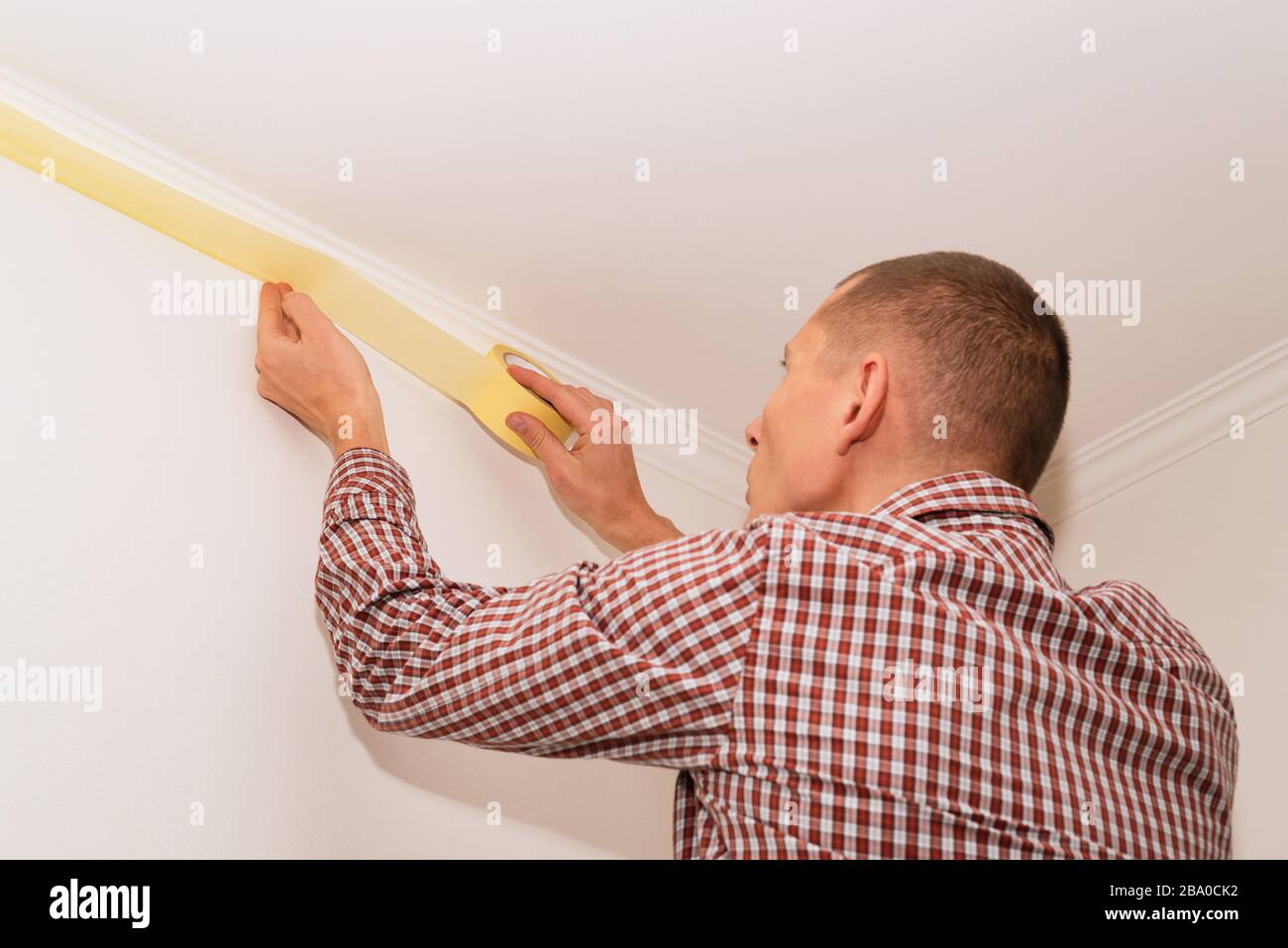 Protéger le plafond avec du ruban de masquage avant de peindre les murs de la pièce Banque D'Images