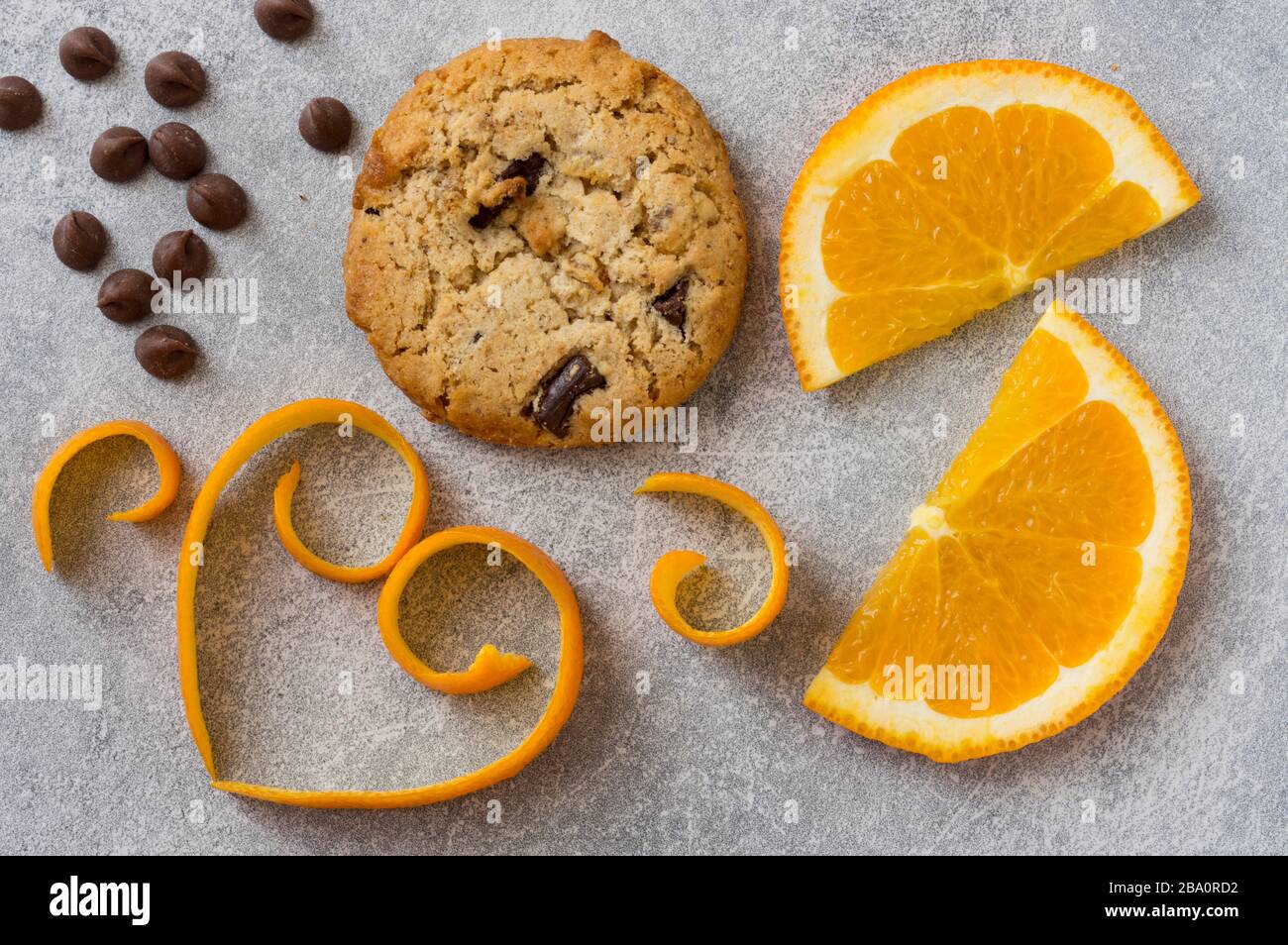 Puce au chocolat et cookie orange. Peau d'orange en forme de coeur sur fond de pierre grise. Banque D'Images