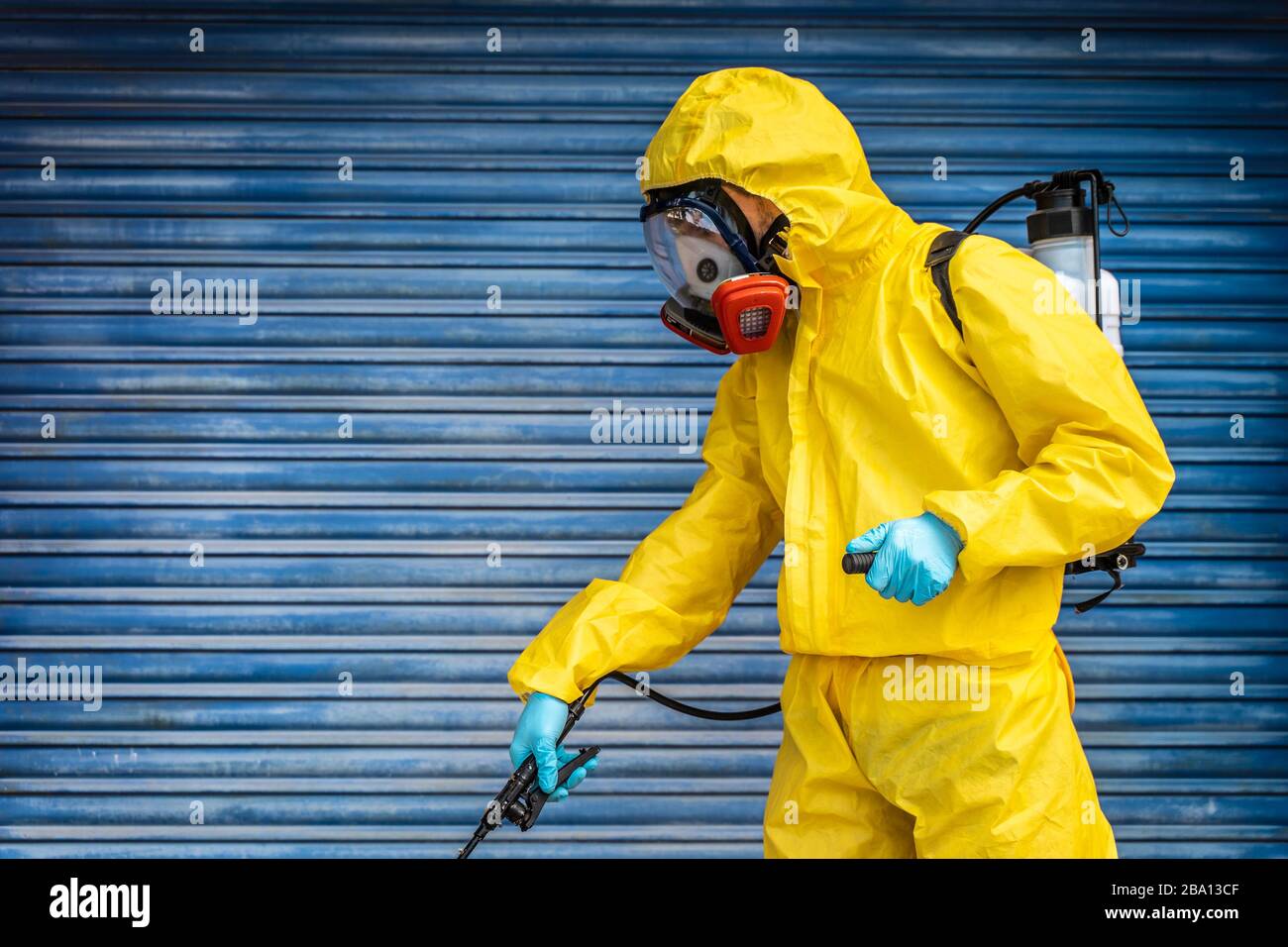Coronavirus. Un agent d'assainissement portant un masque et nettoyant les rues avec une solution à base d'alcool sous pression. Désinfection contre le Corona. Banque D'Images