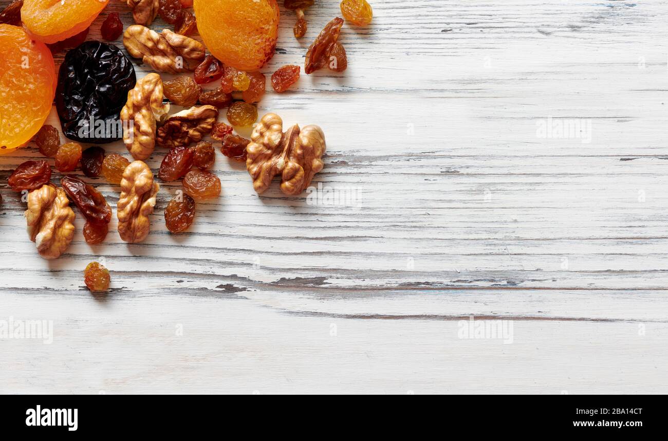 Noix et fruits secs sur une pile sur un fond blanc en bois Banque D'Images