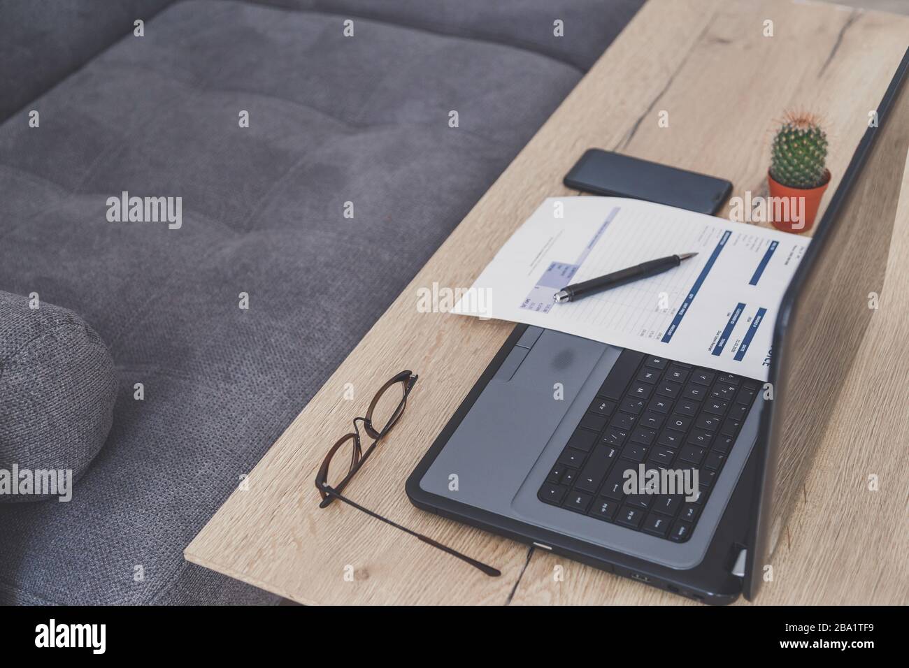 Espace de travail de bureau à domicile. Ordinateur portable, facture et lunettes sur table en bois Banque D'Images