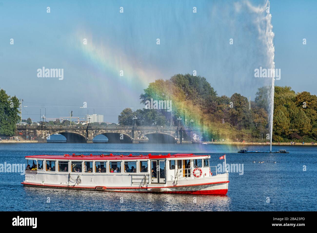 Le cuiseur vapeur Alster se trouve devant la fontaine Alster à Hambourg, avec l'arc-en-ciel Banque D'Images