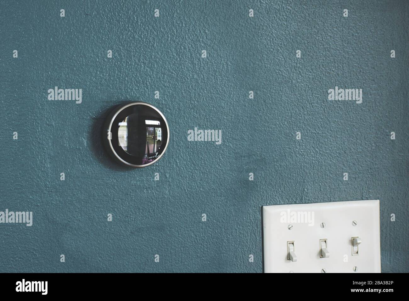 Thermostat sur mur bleu. Isolé sans aucun autre objet autour. Technologie verte et économies de chauffage et de refroidissement. Banque D'Images