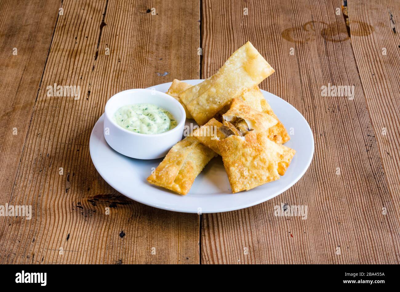 Hors-d'œuvre latino-américain appelé Tequenos fait de wonton frit rempli de fromage et est servi avec du guacamole Banque D'Images