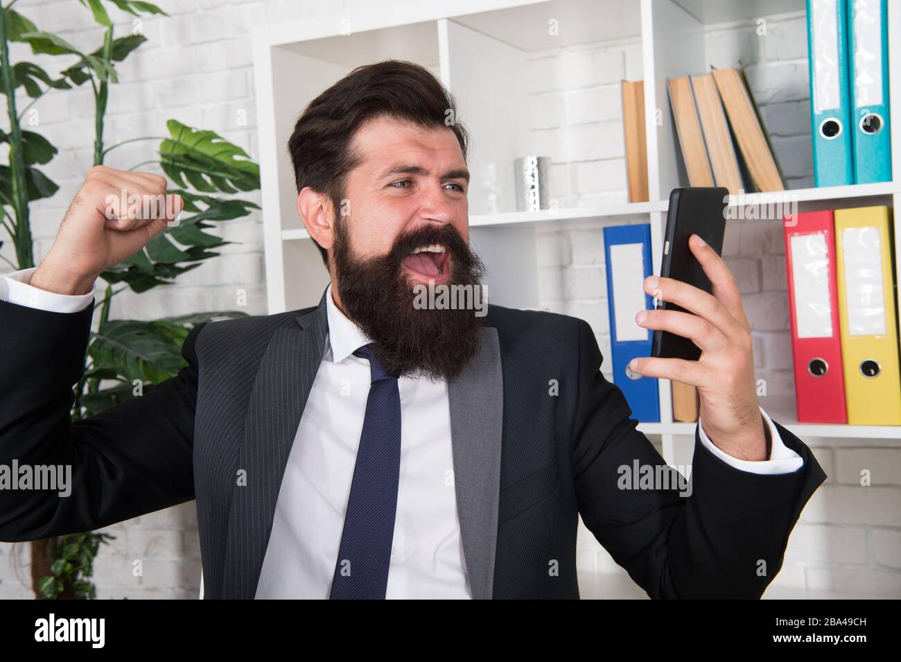 Perdu son tempérament. Smartphone de poinçonner de courtier en colère. L'homme barbu s'est fâché avec des informations sms. Méthode de décontrainte. Soulagement du stress sur le lieu de travail. Se sentir en colère. Mauvaise humeur. Conversation en colère par téléphone. Banque D'Images