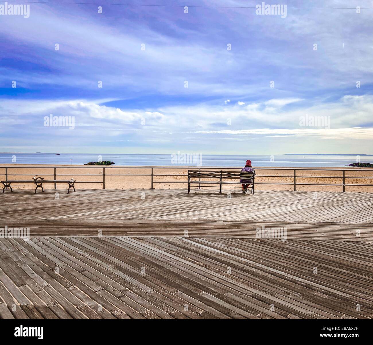 Femme assise sur un seul banc, promenade de Coney Island Banque D'Images