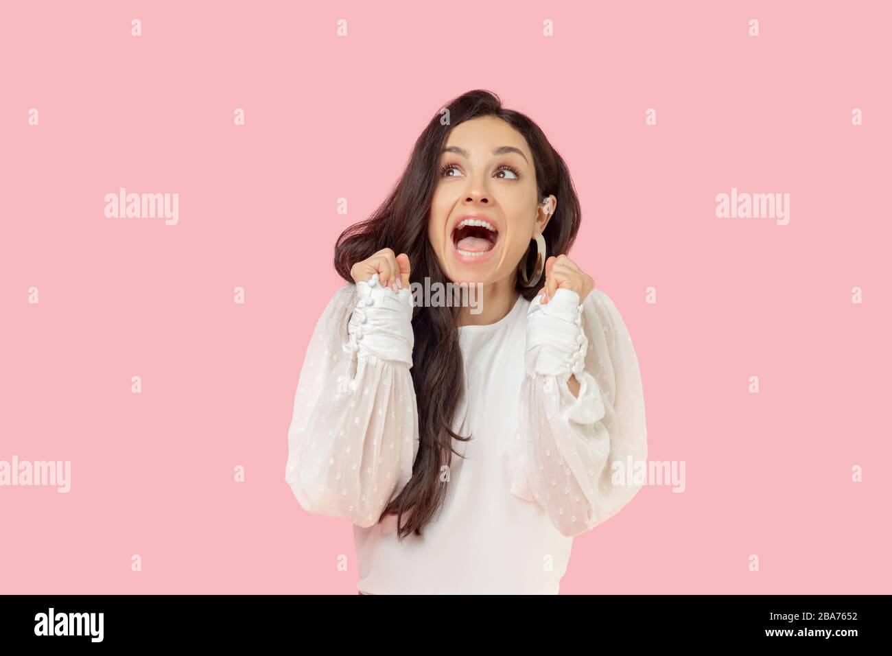 Jeune femme dans un chemisier blanc qui a l'air excitée Banque D'Images