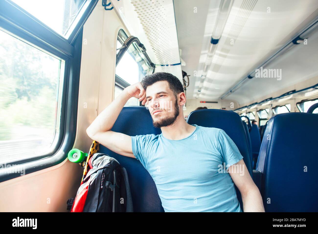 Très jolie hipster moderne guy voyageur sur train avec skateboard seul, le mode de vie des gens vacances concept Banque D'Images