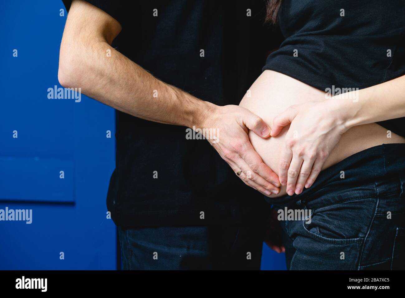 Gros plan de l'homme toucher le ventre de la femme enceinte. Pregeant femme et son mari qui font un coeur avec leurs mains sur son ventre. Banque D'Images