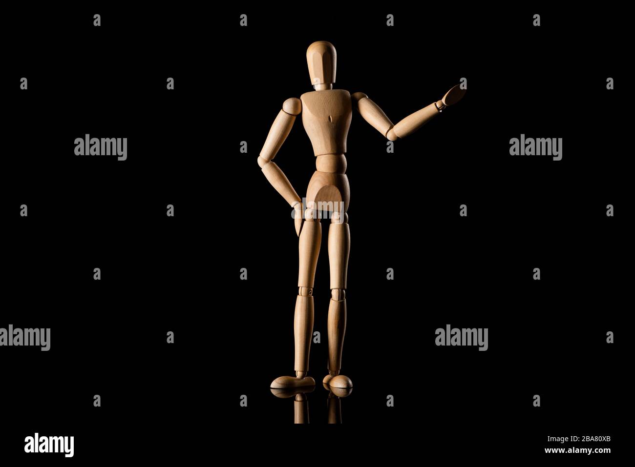 Poupée en bois avec la main sur la hanche imitant pointant avec la main sur fond noir Banque D'Images
