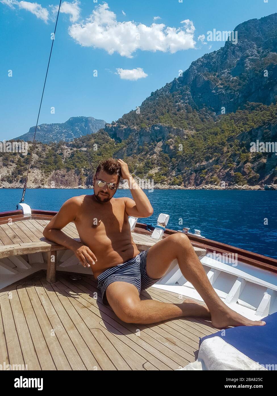 Jeune homme se reposant sur un bateau en bois pendant une excursion en bateau à la plage de papillons à Fethiye Turquie, bronzage jeune garçon en vêtements de natation Banque D'Images