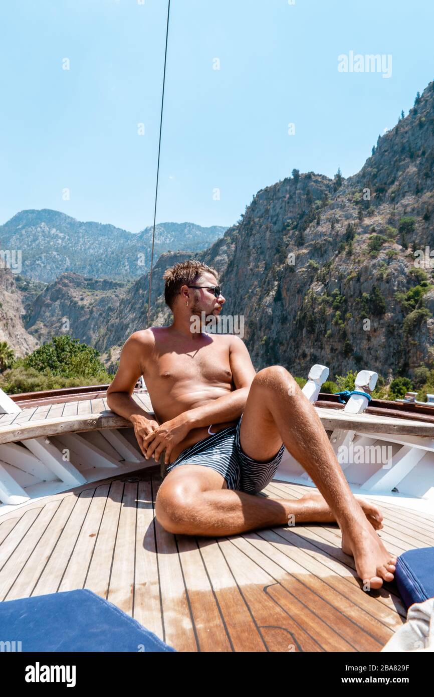 Jeune homme se reposant sur un bateau en bois pendant une excursion en bateau à la plage de papillons à Fethiye Turquie, bronzage jeune garçon en vêtements de natation Banque D'Images
