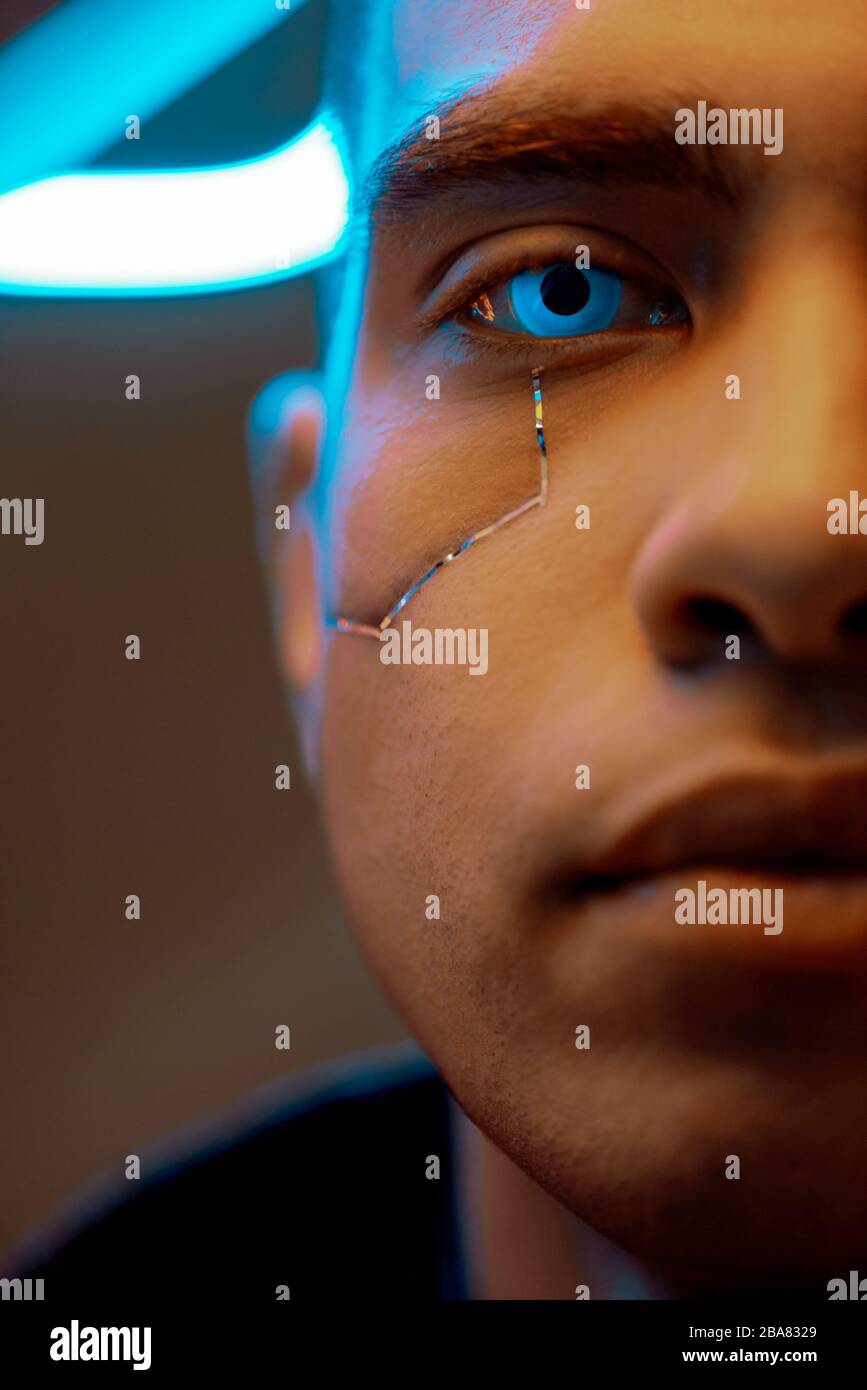 vue recadrée du lecteur de cyberpunk biracial avec des plaques métalliques sur le visage et des yeux bleus regardant l'appareil photo Banque D'Images