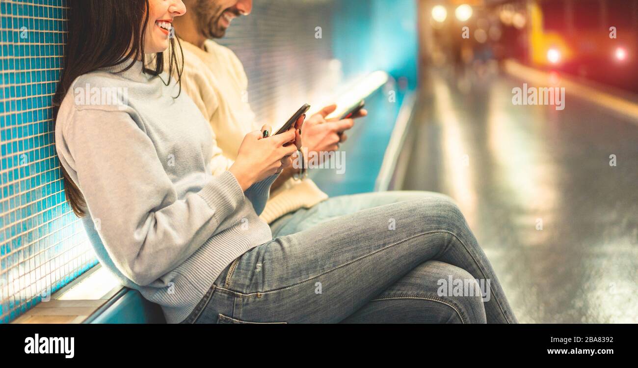 Jeune couple d'amis utilisant des téléphones mobiles à l'intérieur de la station de métro - Millenials les gens qui s'amusent avec les tendances technologiques dans le contexte urbain - Tech Banque D'Images