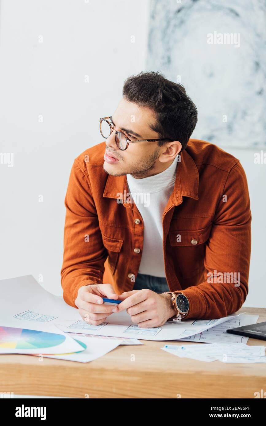 Projet de planification de développeur Pensive ux près des cercles de couleur et des esquisses de conception d'expérience utilisateur sur la table Banque D'Images