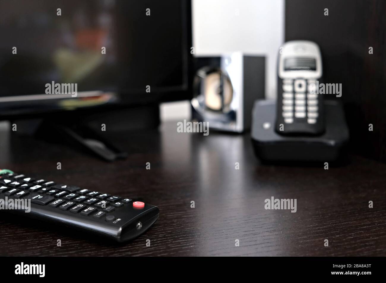 Composition de la technologie : télécommande TV au premier plan (mise au point) et haut-parleur, téléphone sans fil et téléviseur sur fond flou Banque D'Images