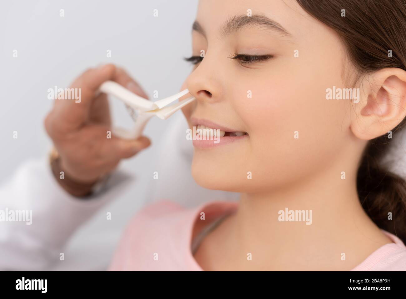 vue rognée d'un médecin traitant examinant le nez d'un enfant souriant avec le spéculum nasal Banque D'Images