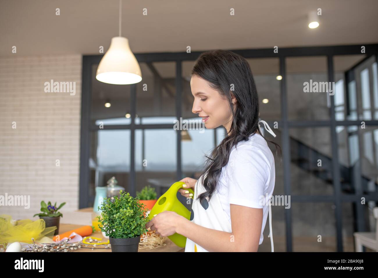 Brunette belle femme arrosant des fleurs dans ses mains Banque D'Images