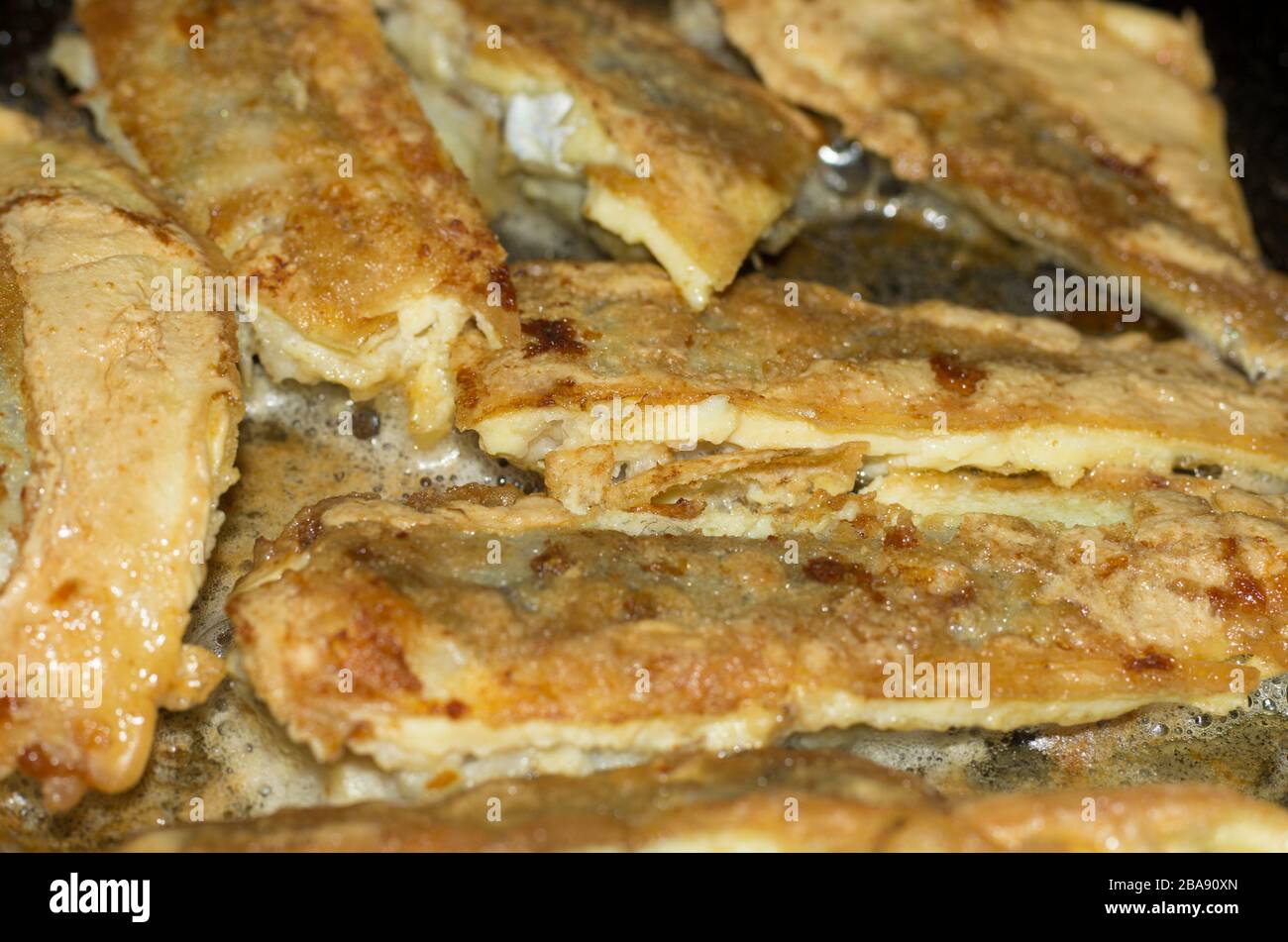 Frit dans des tranches de pâte de Northern Whiting dans une poêle à frire avec de l'huile Banque D'Images