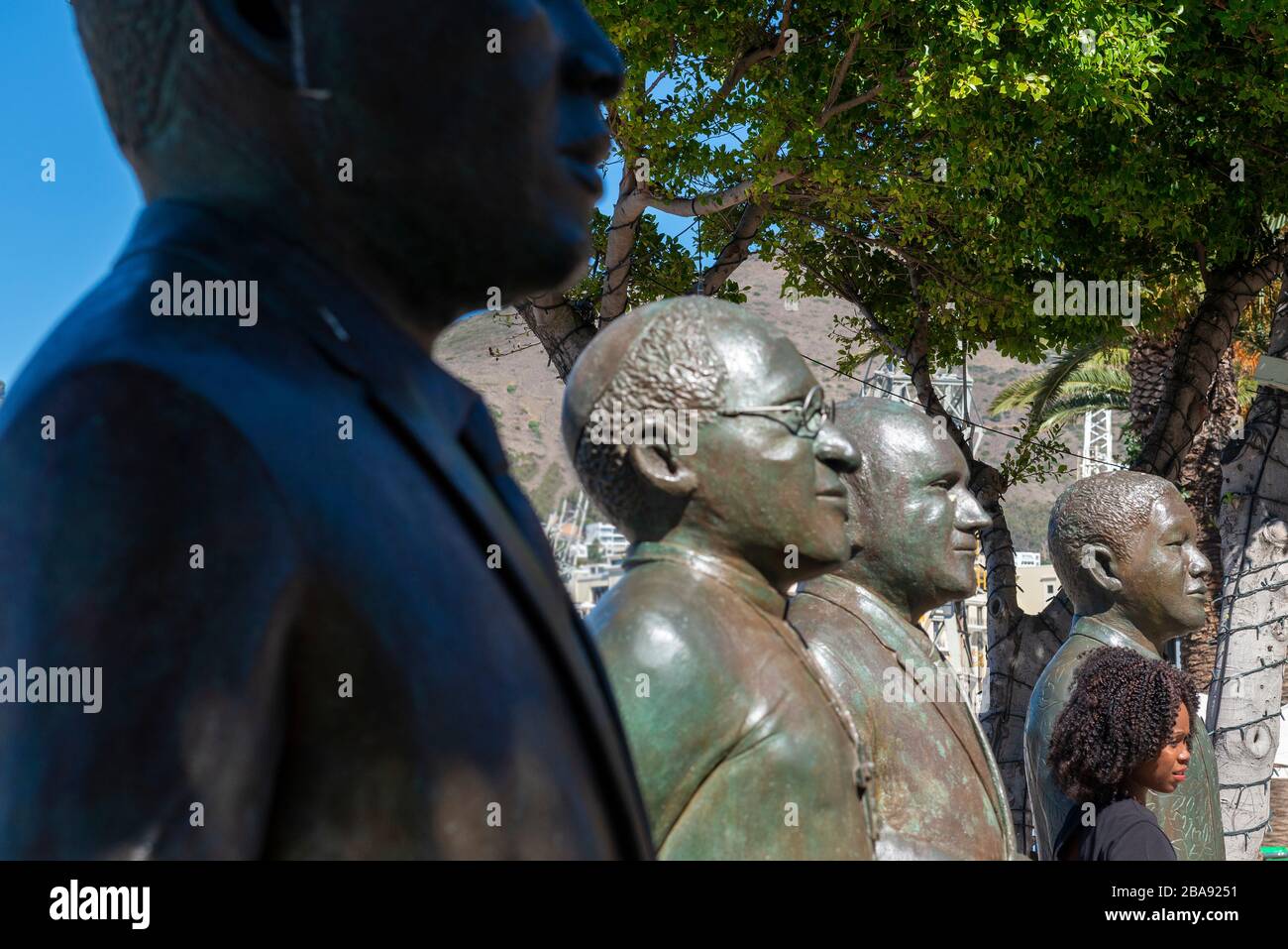 Fille noire debout avec les statues des quatre lauréats du prix Nobel de la paix du pays sur la place Nobel, V&A Waterfront, le Cap, Afrique du Sud Banque D'Images