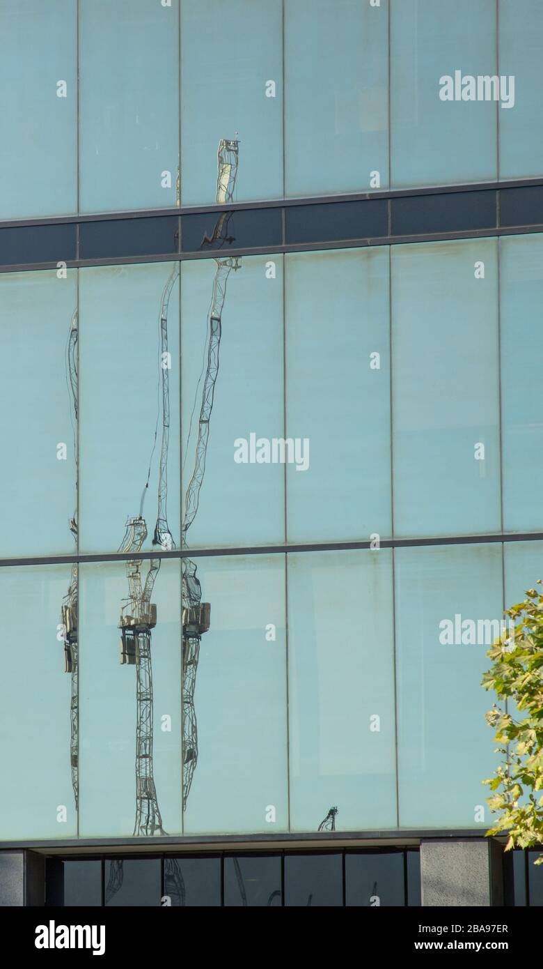 Reflets de grues hautes vues sur les fenêtres en verre des grands bâtiments de gratte-ciels de bureaux. Banque D'Images