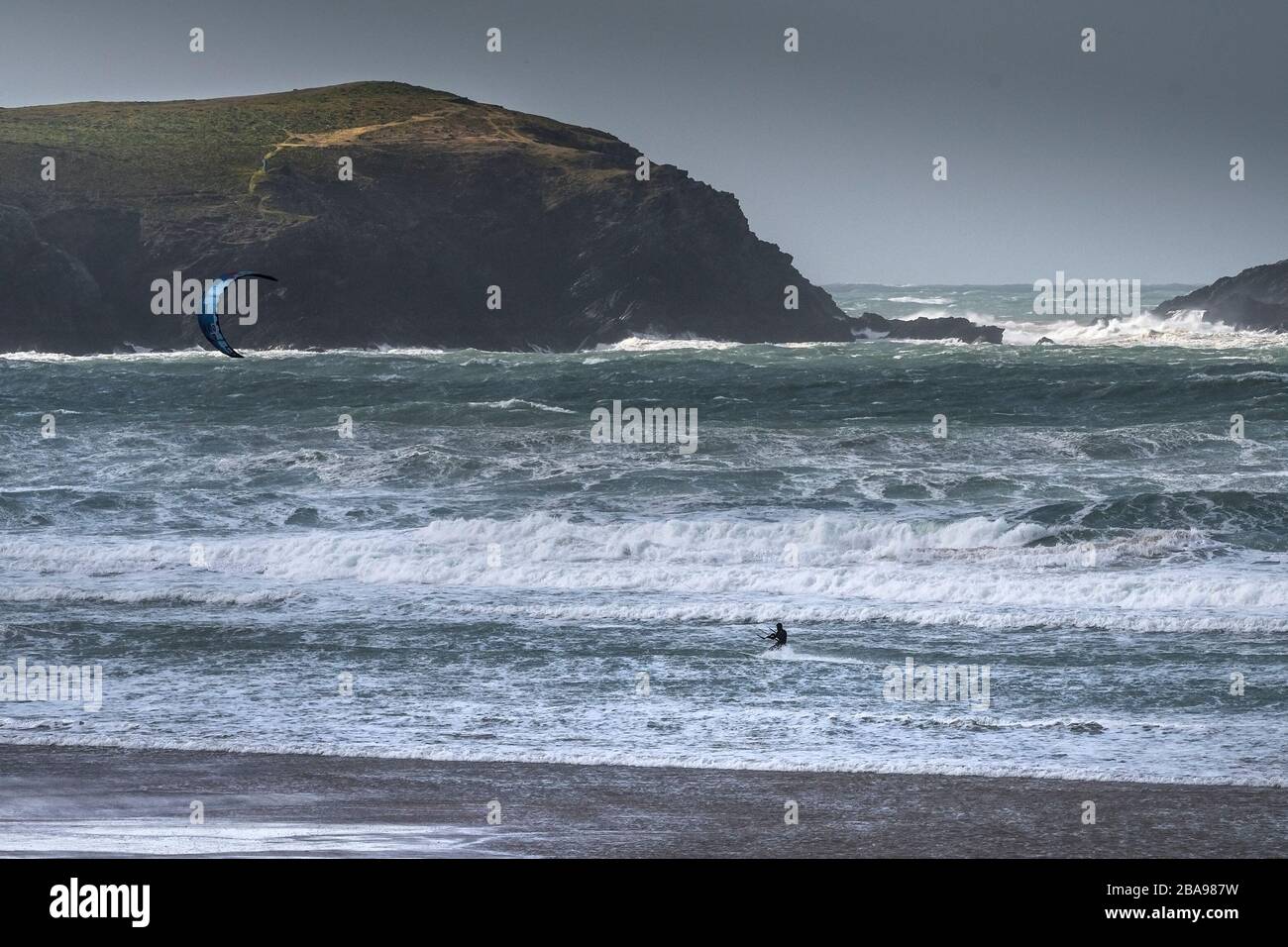 Un surfeur de kite solitaire bravant les conditions venteuses sauvages à Fistral, à Newquay, en Cornwall. Banque D'Images