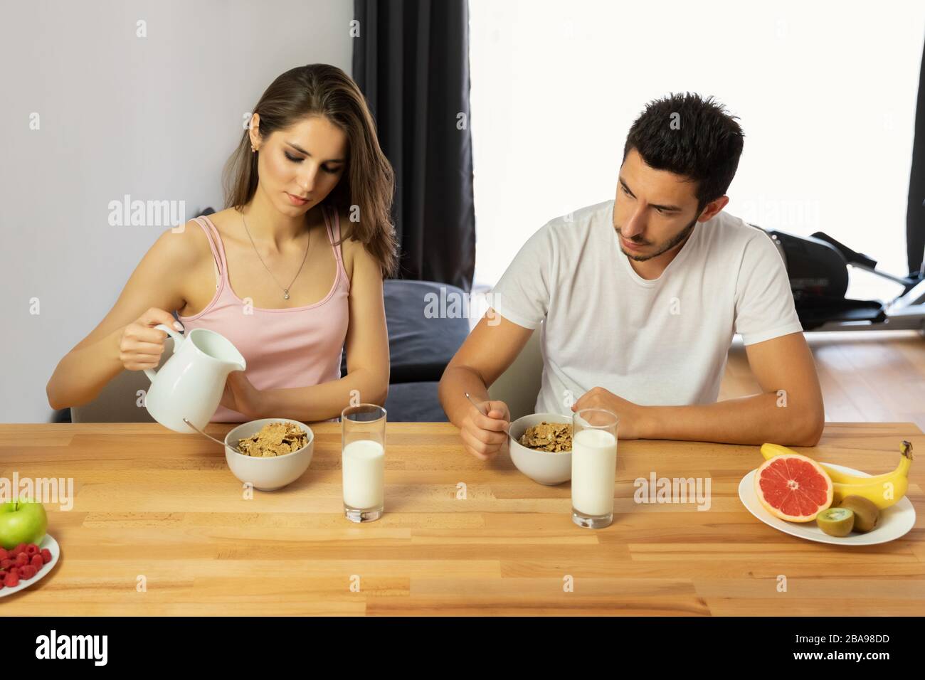 Un jeune couple magnifique mange des céréales pour le petit déjeuner avec des baies et du lait. Alimentation correcte, petit déjeuner équilibré. Banque D'Images