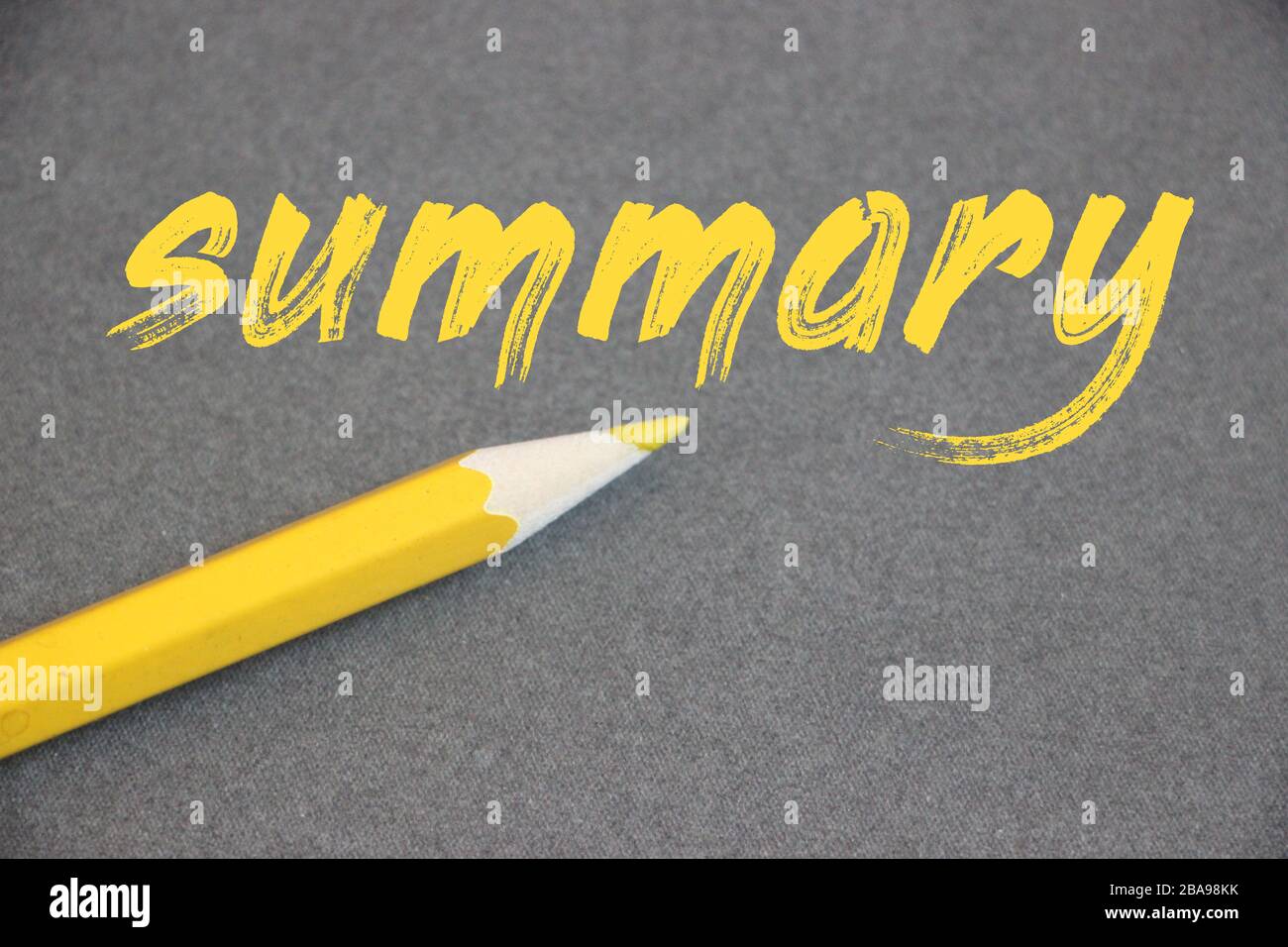 Résumé mot main écrit en lettres jaunes avec crayon en plus sur fond gris. Photo d'entreprise bref résumé Synopsis concept concis Banque D'Images