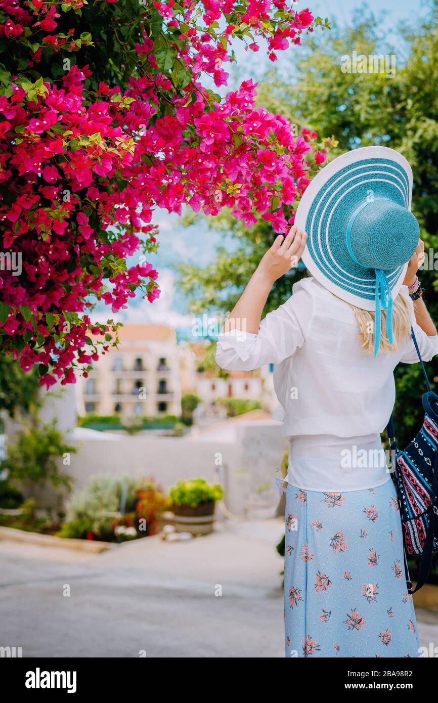 Femme adulte avec chapeau bleu Profitez de fleurs vives dans la jolie ville d'Assos sur l'île de Céphalonie. Super été sur la mer méditerranée. Voyage romantique vac Banque D'Images