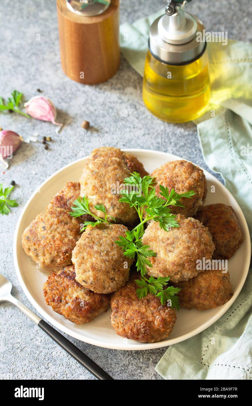 Délicieux côtelettes de viande juteuse maison en assiette, boulettes de viande hachées sur une table en pierre grise. Banque D'Images