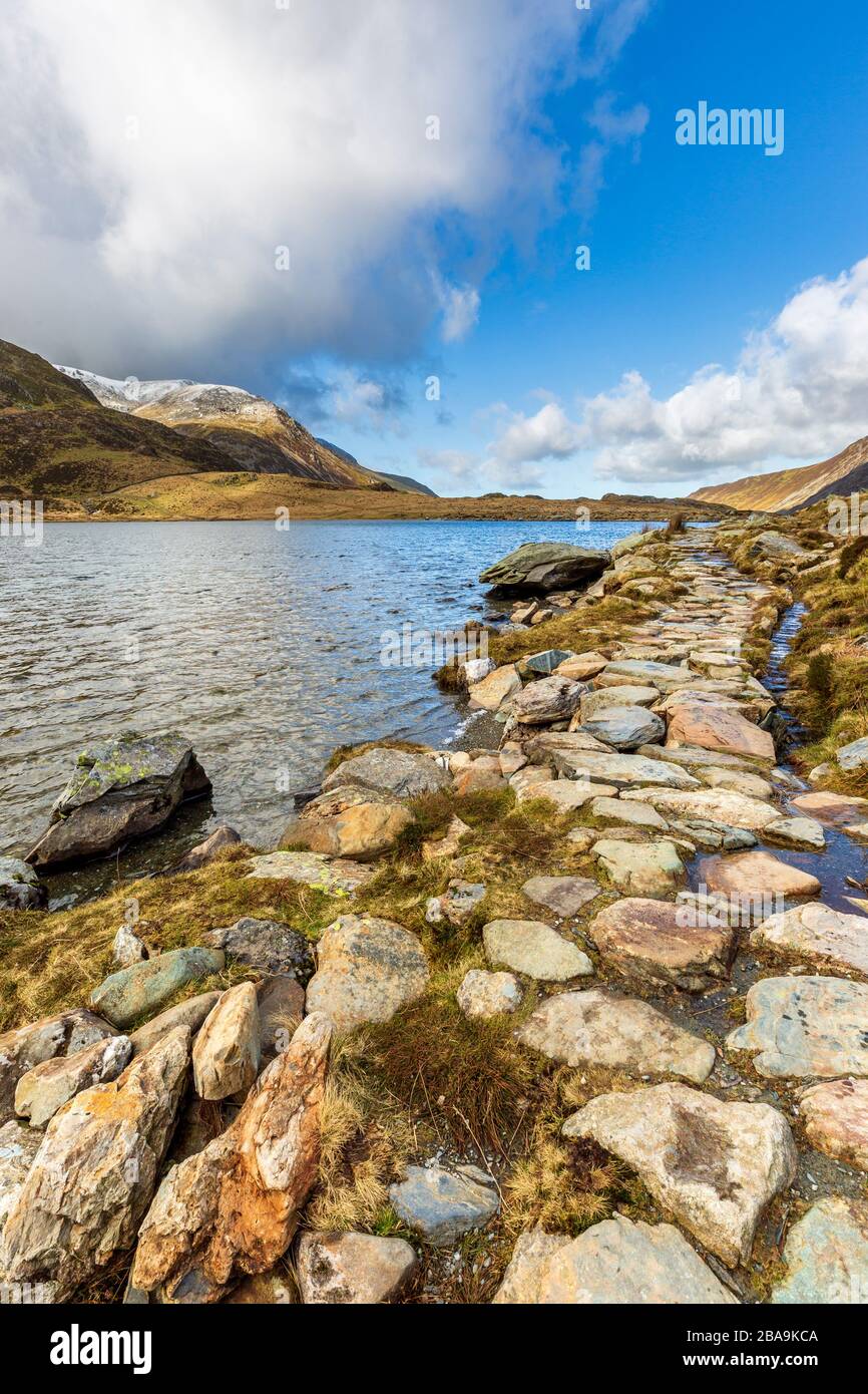 Des pierres à pas autour du lac Idwal et des montagnes enneigées de Snowdonia, au Pays de Galles Banque D'Images