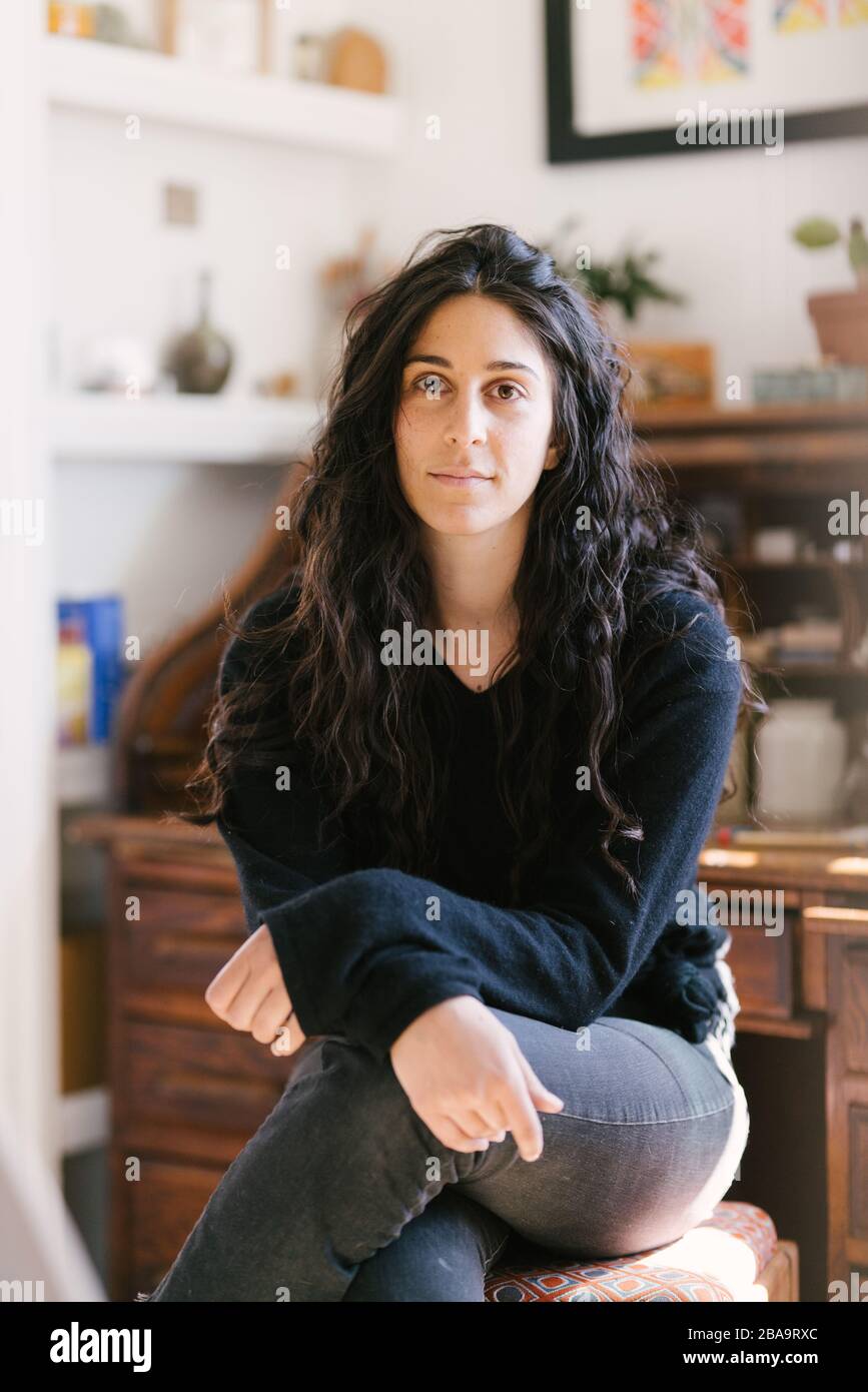 Portrait d'une femme assise dans l'appareil photo avec les cheveux dans la maison Banque D'Images