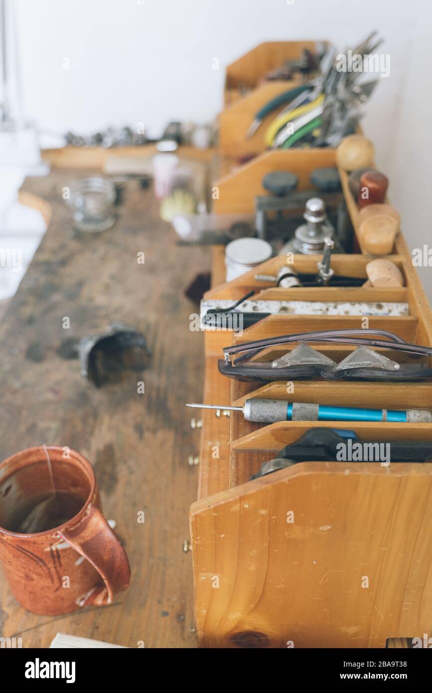 Détail des outils assortis utilisés pour la fabrication de bijoux sur un banc de travail en bois Banque D'Images