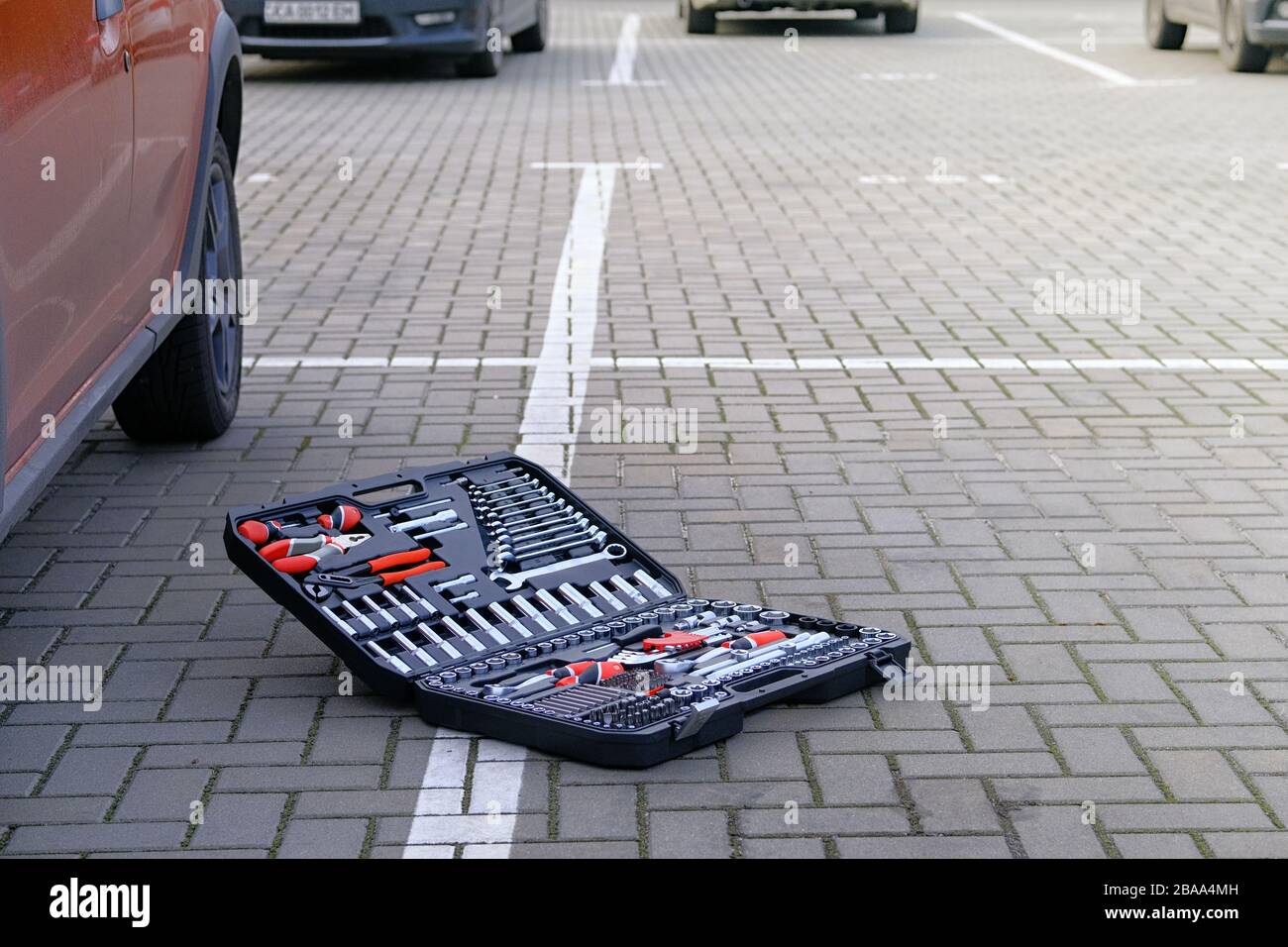 Divers outils pour la réparation et le diagnostic d'une voiture. Jeu d'outils dans la boîte près de la voiture orange dans le parking. Concept d'entretien automobile. Banque D'Images Divers outils pour la réparation et le diagnostic d'une voiture. Jeu d'outils dans la boîte près de la voiture orange dans le parking. Concept d'entretien automobile. Banque D'Images