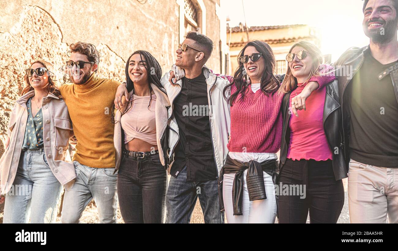 Concept d'unité et de cohésion des jeunes multiraciaux embrassant ensemble. Des amis de différentes courses marchent ensemble mains sur les épaules en plein air Banque D'Images