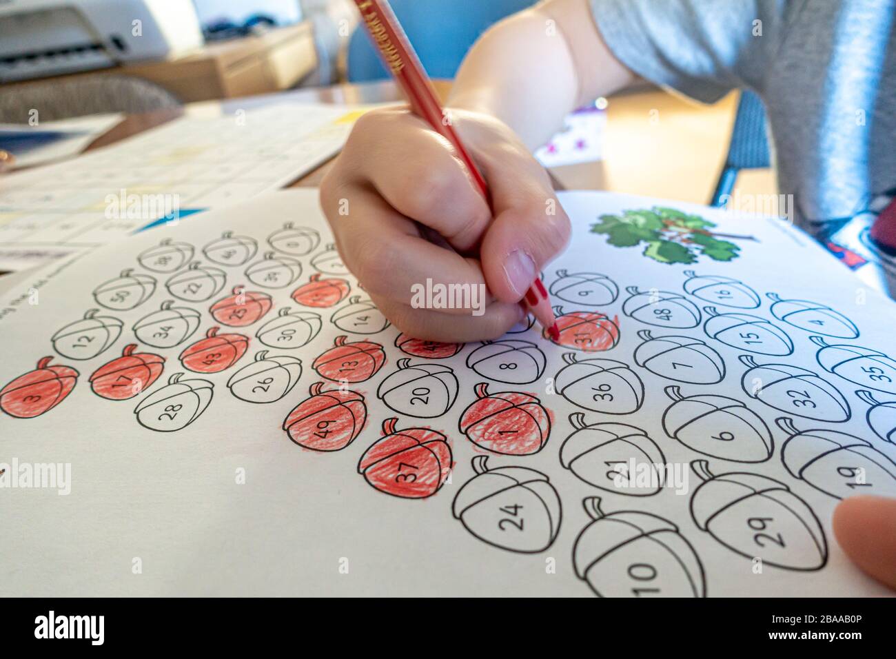 Vue rapprochée de la main d'un jeune enfant utilisant un crayon de couleur pour colorer en nombres impairs dans le cadre d'une éducation à la maison en raison de la pandémie de coronavirus. Banque D'Images