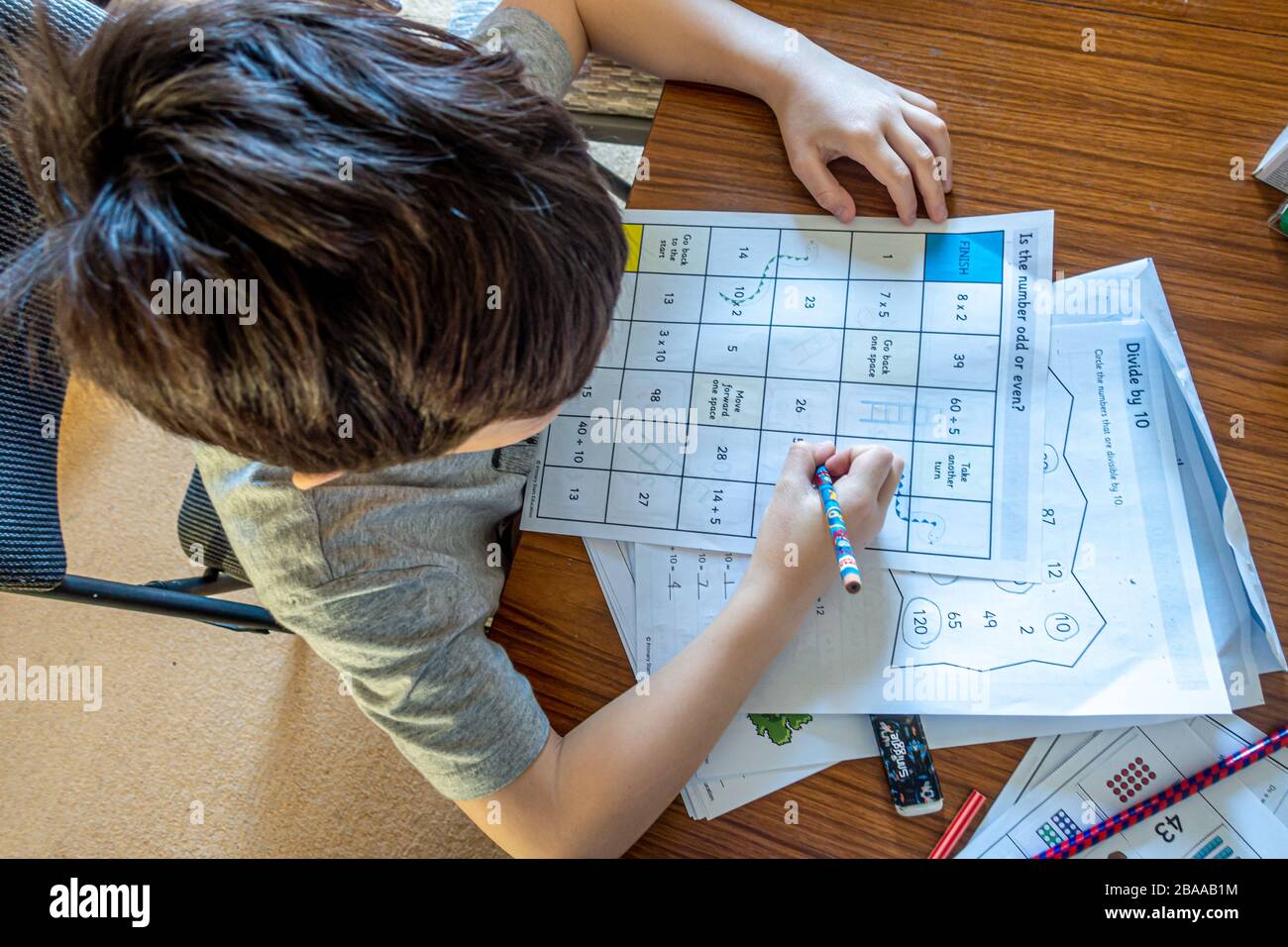 Un jeune garçon travaillant sur des énigmes mathématiques dans le cadre d'un jeu thématique de mathématiques. Cela fait partie de l'apprentissage à domicile à la suite de la pandémie de coronavirus. Banque D'Images