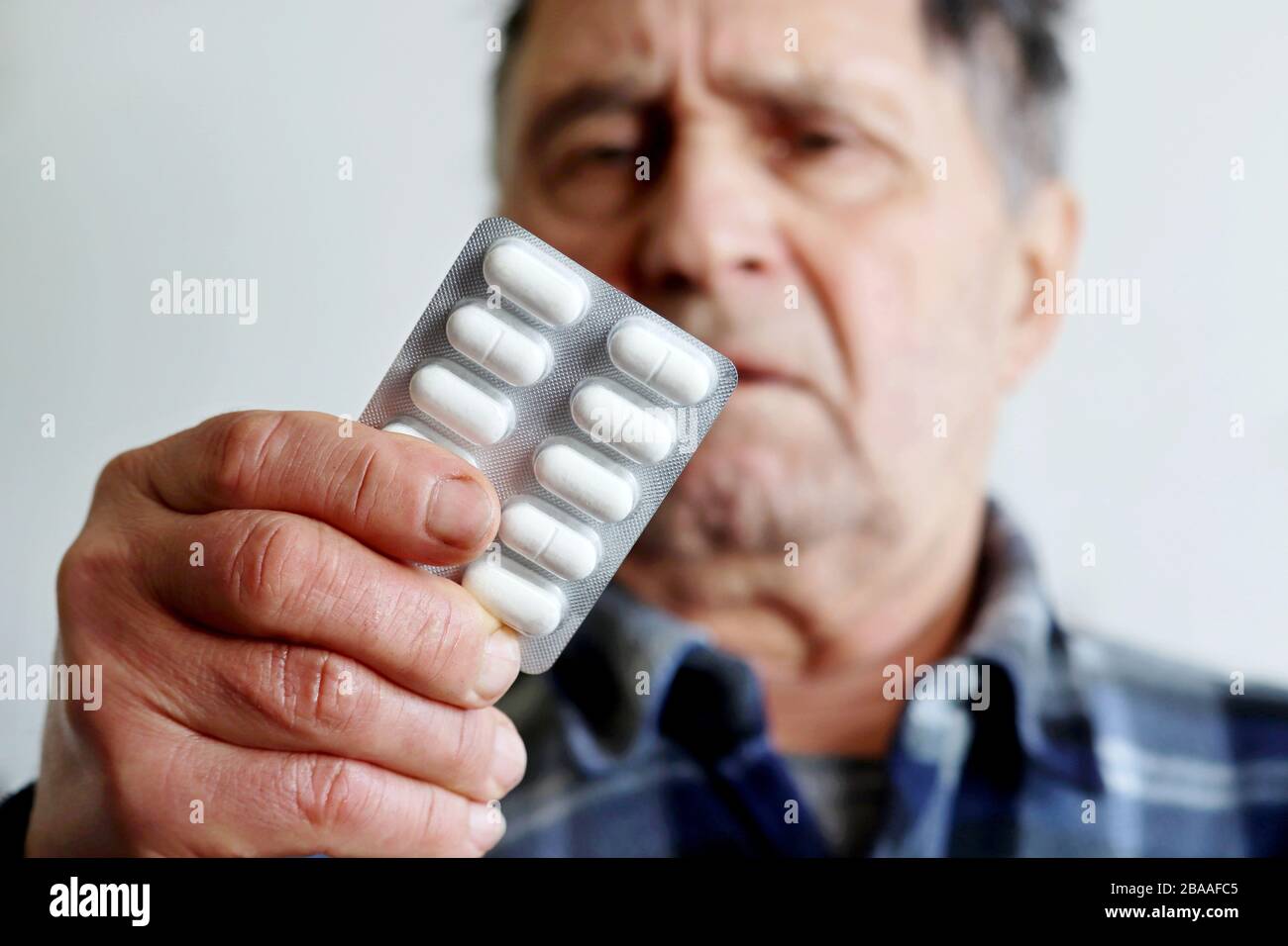 Traitement et prévention du coronavirus, homme âgé avec pilules blanches en plaquettes thermoformées. Concept de prescription médicale, rhume et grippe, maladie d'Alzheimer Banque D'Images