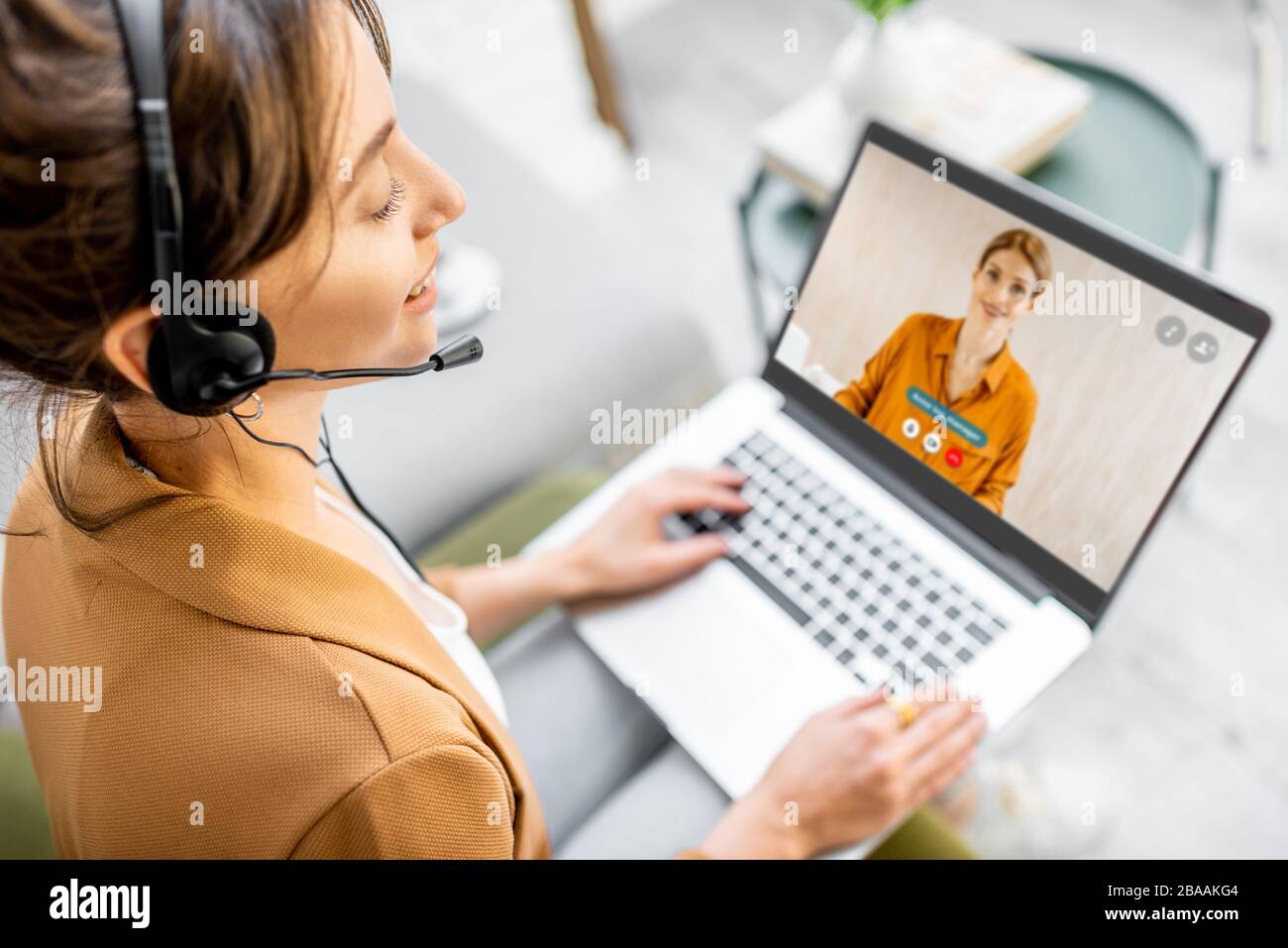 Femme d'affaires ayant un appel vidéo avec un collègue, travaillant en ligne à partir de la maison à l'atmosphère confortable. Concept de travail à distance à domicile Banque D'Images