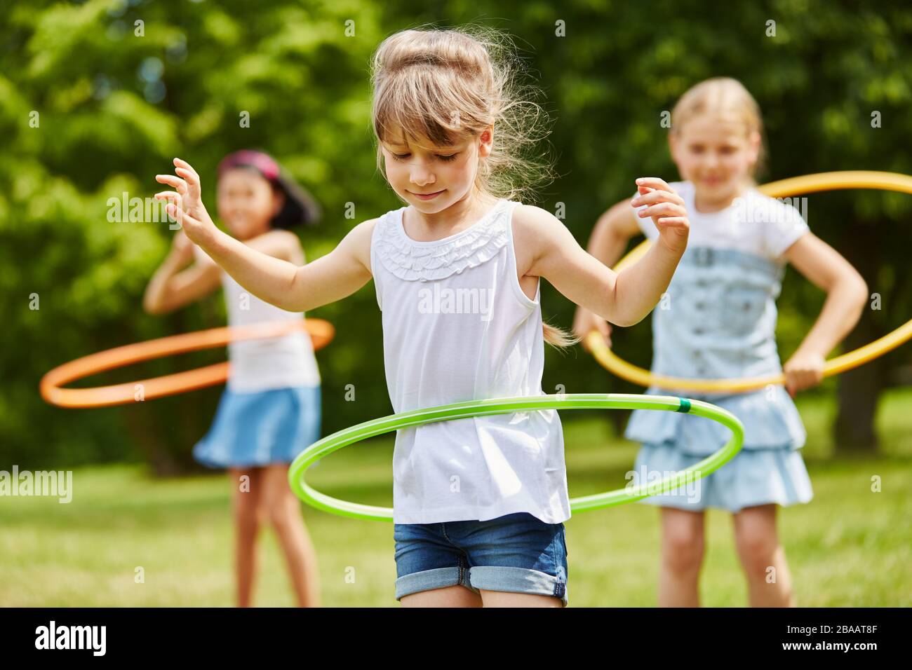 Trois enfants jouent avec des pneus à la maternelle en été Banque D'Images