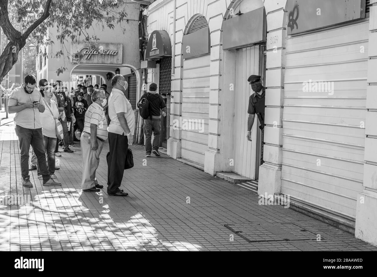 Les gens qui attendent dans les rues de Providencia pour entrer dans les banques et les magasins au cours des dernières heures avant le couvre-feu parce que la maladie de coronavirus COVID-19 Banque D'Images