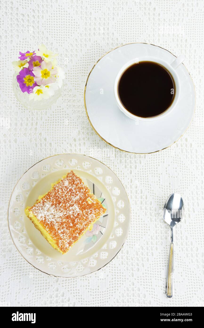 Gateau Grec Ravani Avec Une Tasse De Cafe Noir Une Cuillere Et Un Petit Vase Avec Des Fleurs Primula Sur Fond De Dentelle Mate Photo Stock Alamy