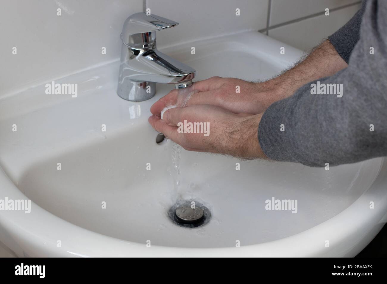 Détail d'un jeune homme se lavant les mains avec du savon sous l'eau courante afin de réduire le risque d'infection pendant la pandémie du virus corona Banque D'Images