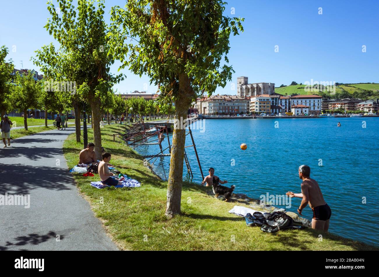 Zumaia, Gipuzkoa, Pays basque, Espagne - 15 juillet 2019 : Père et fils jouent un jeu de balle dans l'estuaire de ria del Urola avec l'église de SanPedro i Banque D'Images