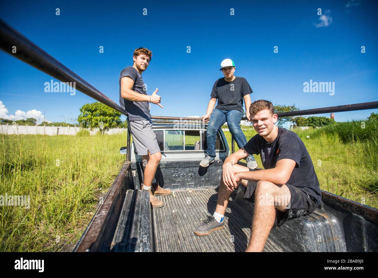 Trois jeunes hommes se trouvent dans le lit d'un 4x4, en Amérique centrale rurale. Banque D'Images