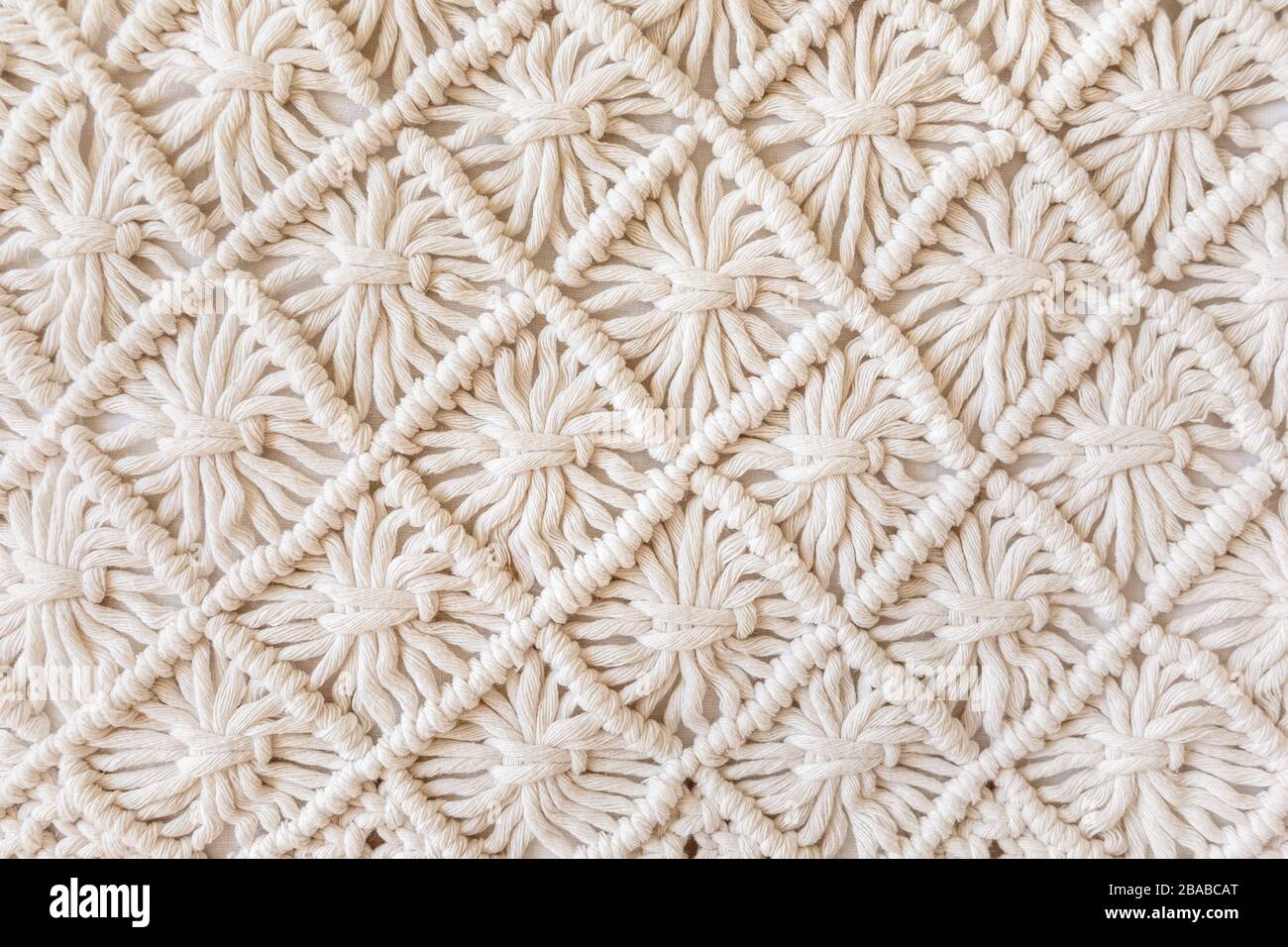 Gros plan du motif de texture macrame fait à la main. ECO amical moderne tricot DIY décoration naturelle concept. Pose plate. Banque D'Images