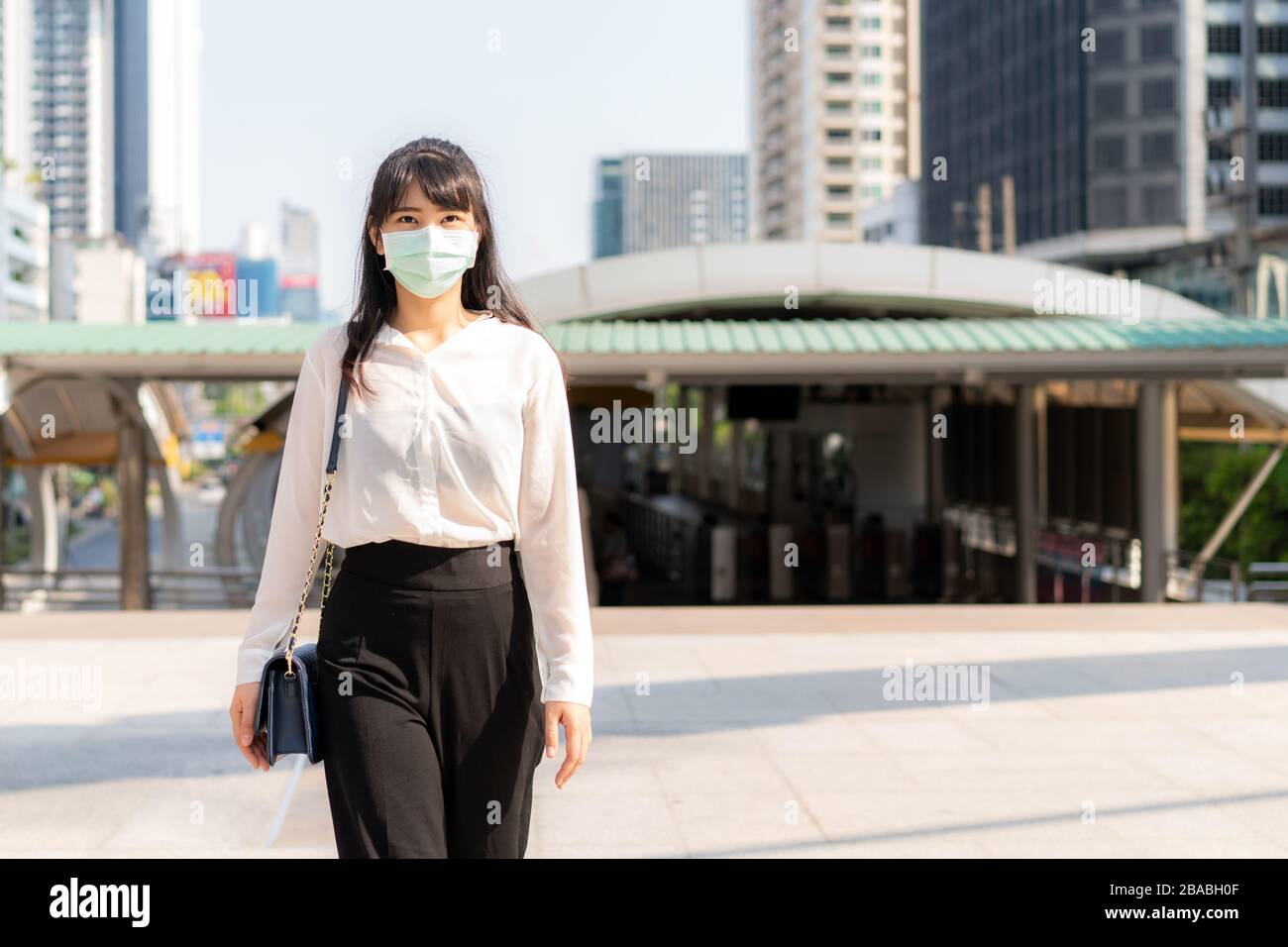 Jeune femme d'affaires asiatique de stress en chemise blanche qui va travailler dans la ville de pollution, elle porte un masque de protection pour prévenir la poussière, le smog, la pollution de l'air et les PM2,5 Banque D'Images