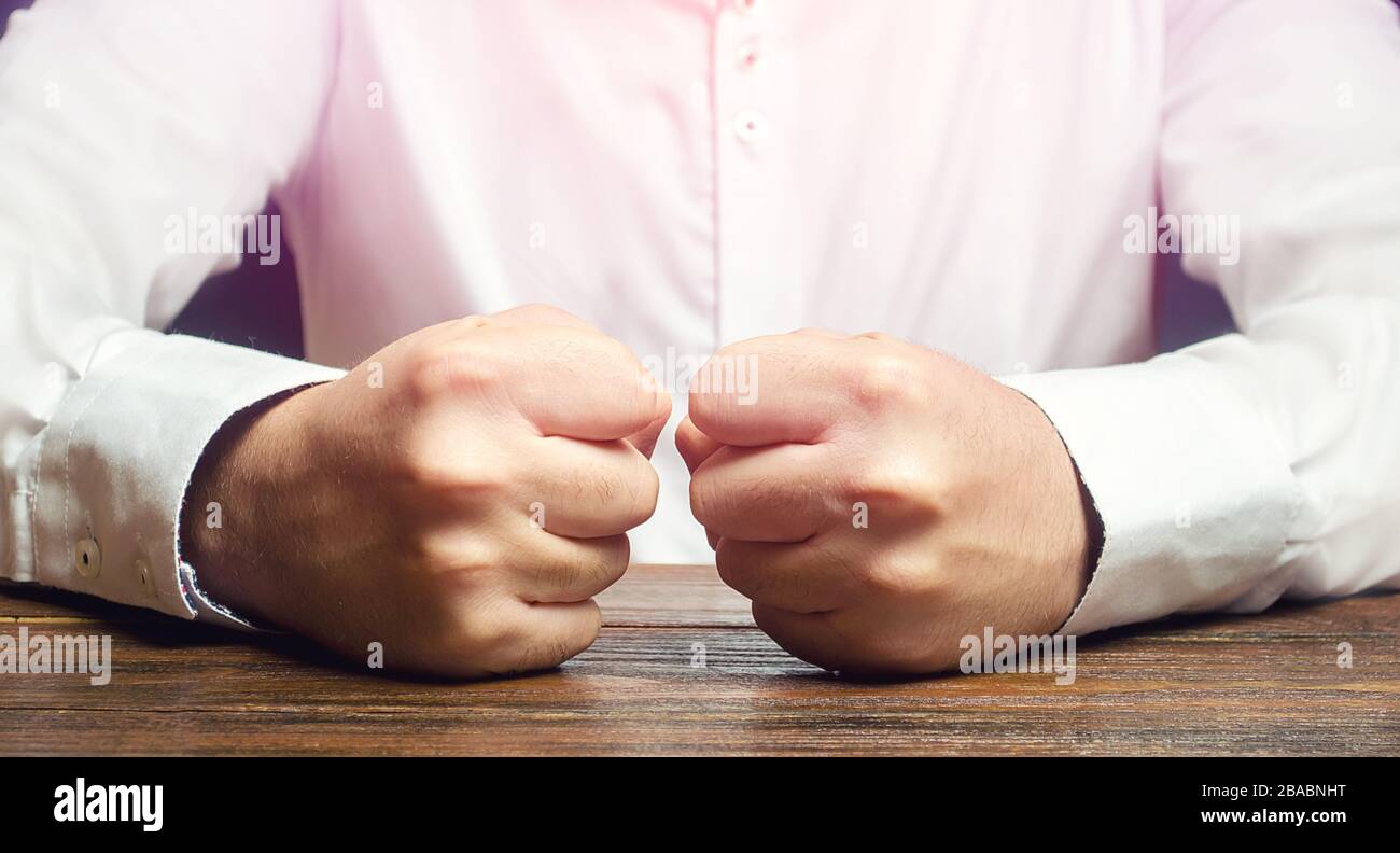 Un homme tient ses poings fermés sur la table. Une attaque de colère, de stress. Un geste décisif et émotionnel. Hommes impulsifs. Souffrir de la défaite, de l'échec et des los Banque D'Images
